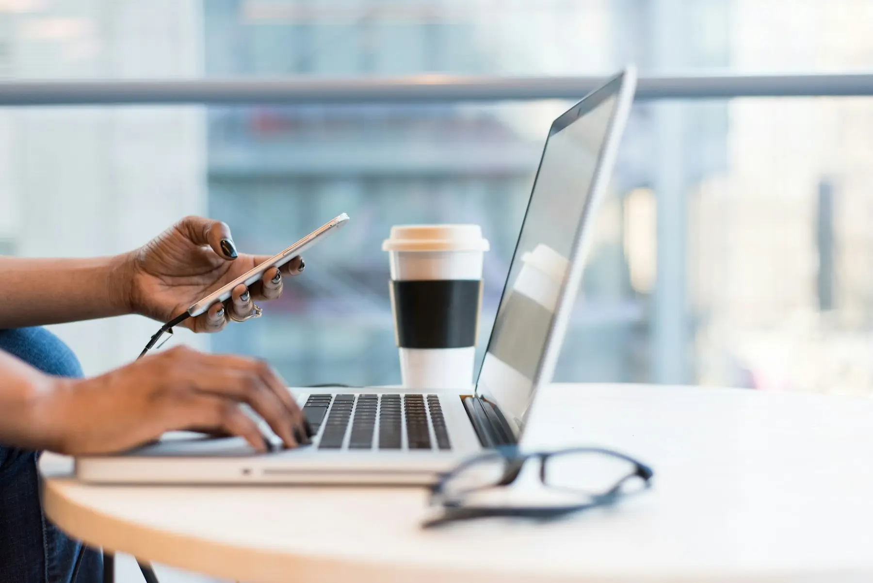 A web designer working between a laptop and smartphone